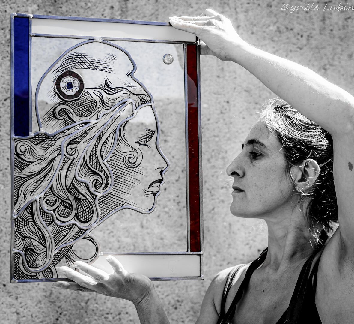 Magali Bauchy dans son atelier, tenant l'un de ses vitraux