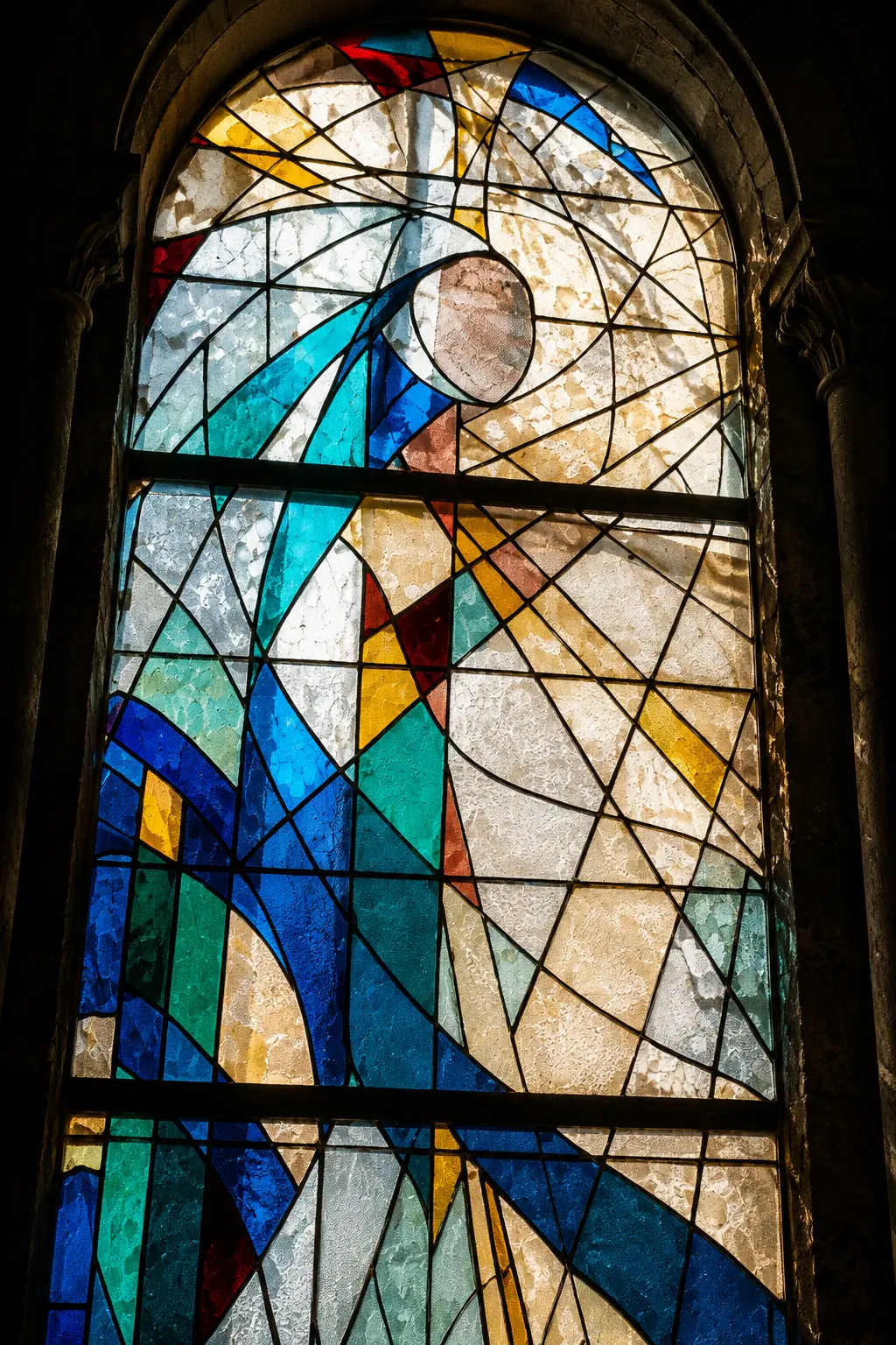 Vitrail contemporain figuratif aux teintes bleues, turquoises et dorées, dans une arcade de pierre